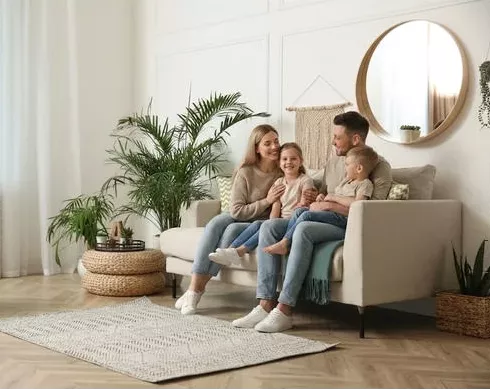 A family of four sitting together on the sofa in the living room of a Legacy Signature Rentals home