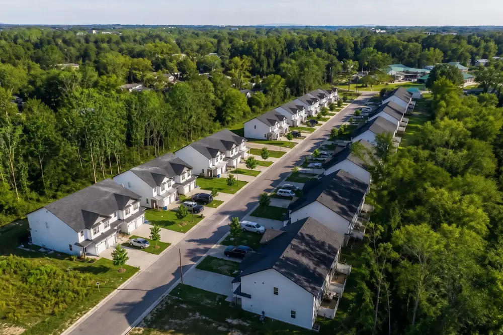 Aerial view of two rows of new townhomes with driveways and garages on a tree-lined street in Northeast Hickory