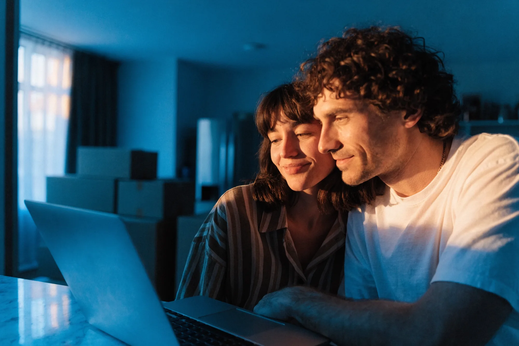 A couple filling in the Obligo application on a laptop at home, moving boxes behind them