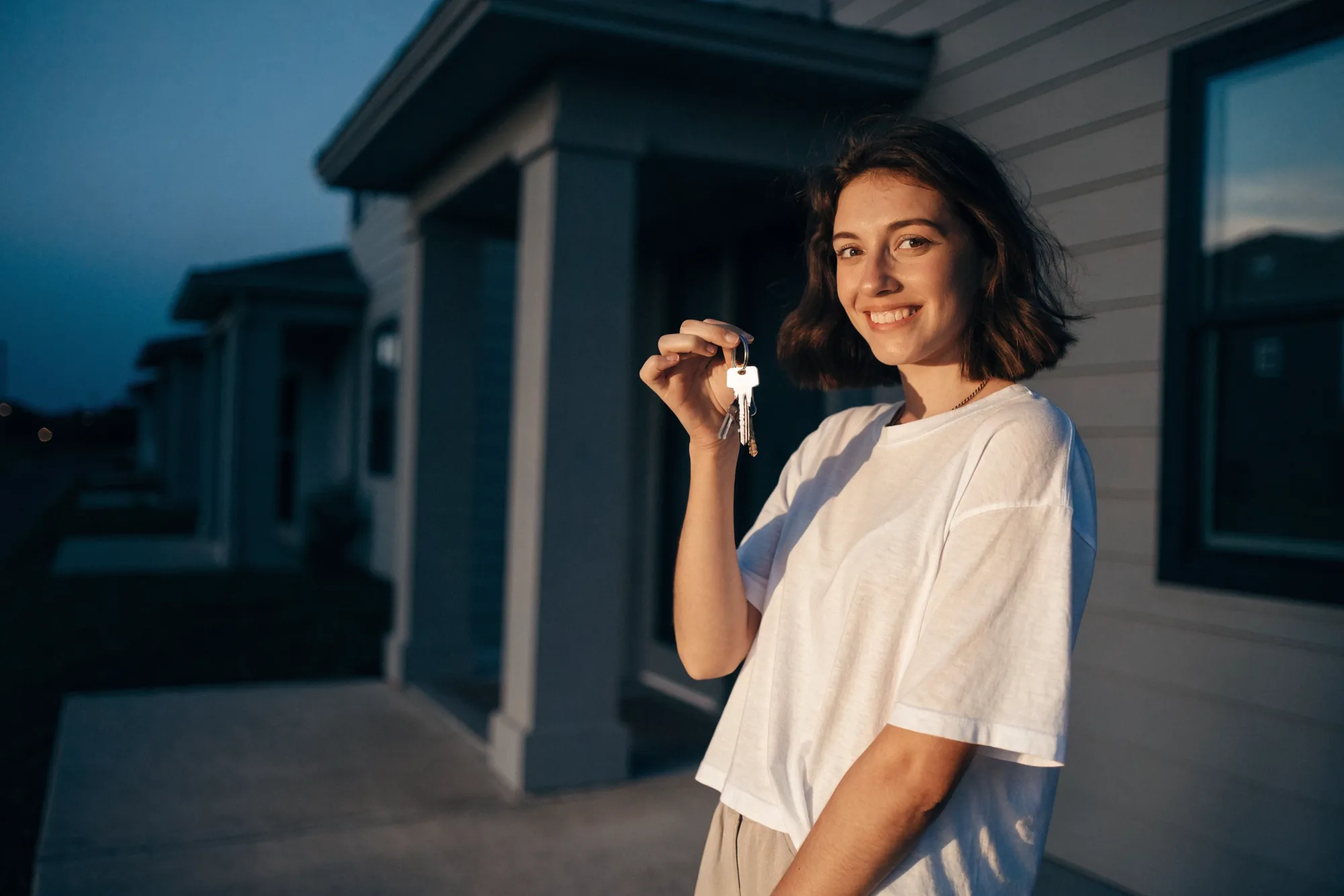 A new resident on the porch of a Legacy Signature Rentals home, holding the keys after a deposit-free move-in
