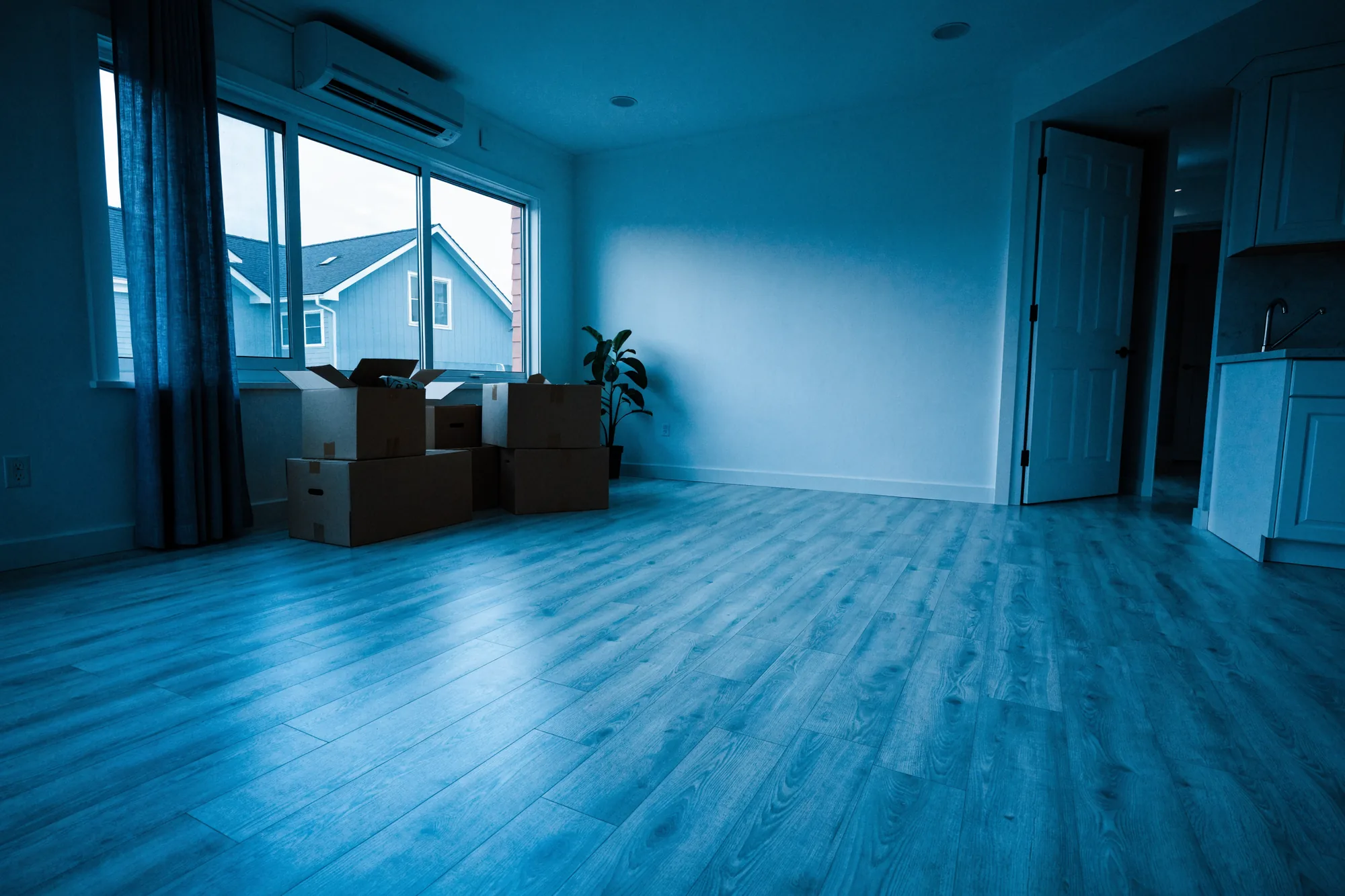An empty living room in a new Legacy Signature Rentals townhome on move-in day with a few moving boxes by the window
