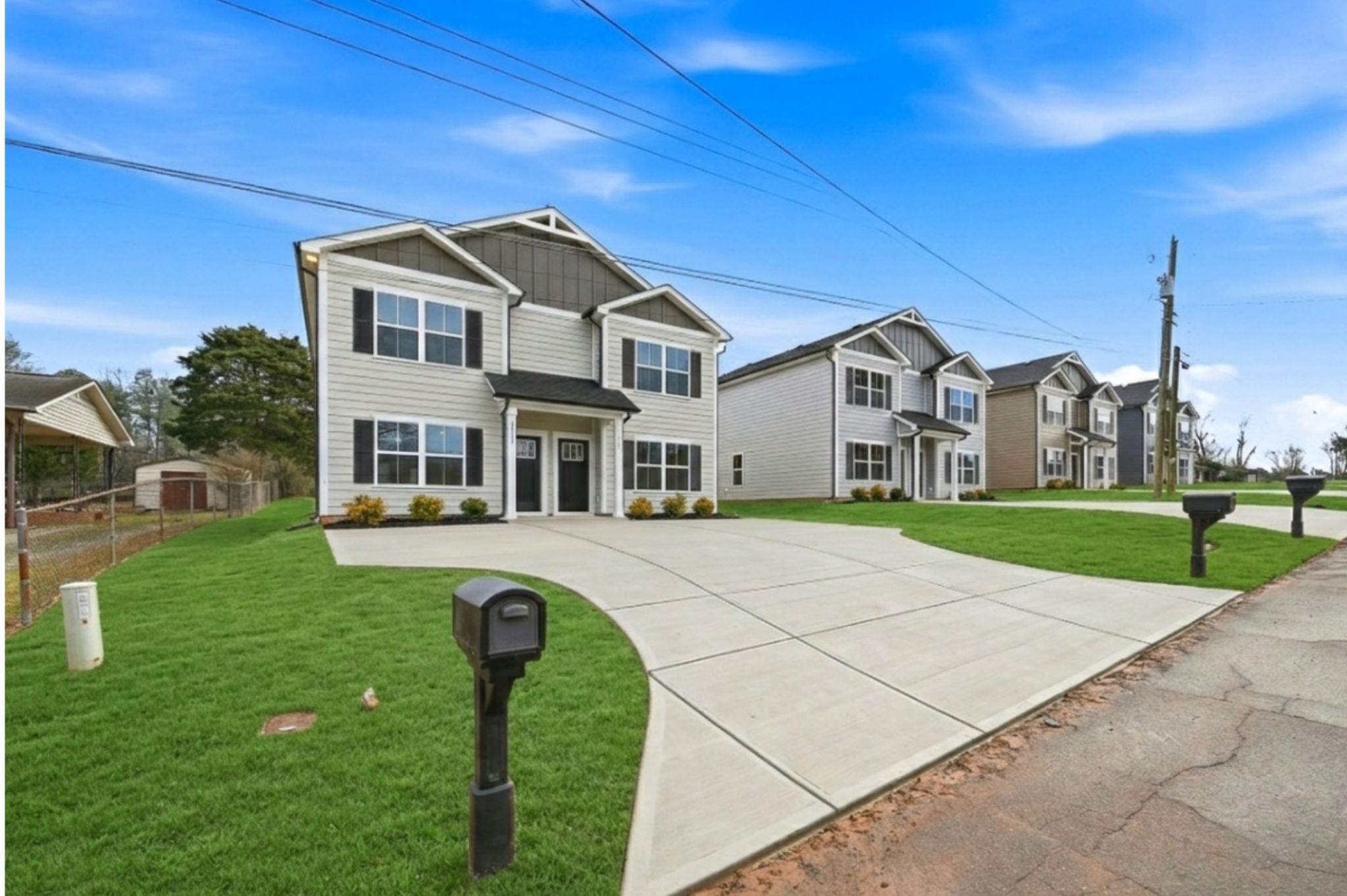 Street of new Legacy Signature Rentals townhomes with fresh green lawns and wide driveways