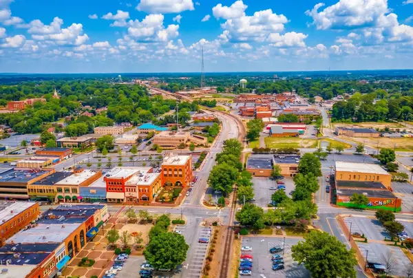 Aerial view of downtown Hickory, NC — brick storefronts along the main street, a rail line running through the centre, and wooded hills on the horizon