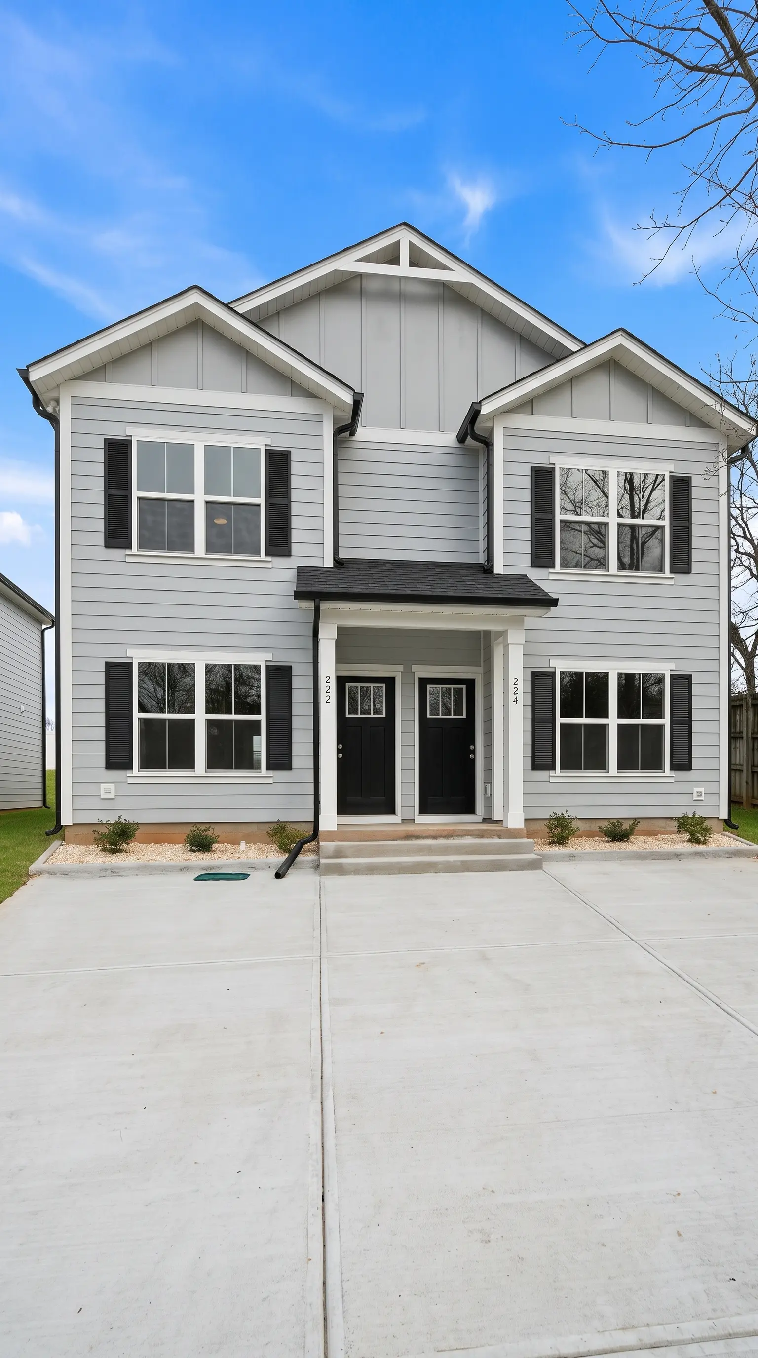Front elevation of a Legacy Signature Rentals two-unit home for rent in Hickory, NC — light grey siding with white trim, black shutters and two black front doors