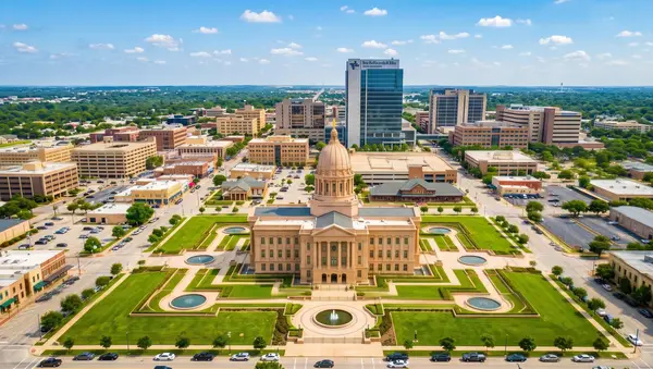 Aerial view over downtown Temple, TX — a domed civic building on formal lawns with fountains and tree-lined walks, low-rise blocks and a glass office tower behind it